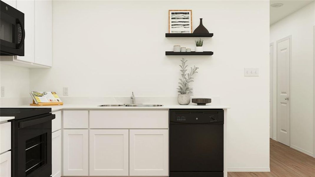 Kitchen with light hardwood / wood-style floors, white cabinets, black appliances, and sink