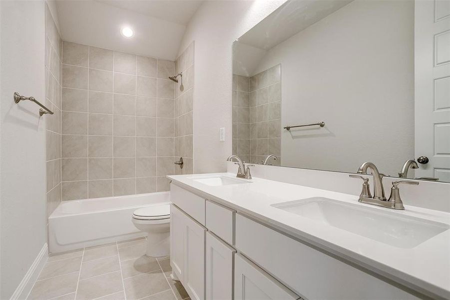 Full bathroom featuring tiled shower / bath, vanity, toilet, and tile patterned floors