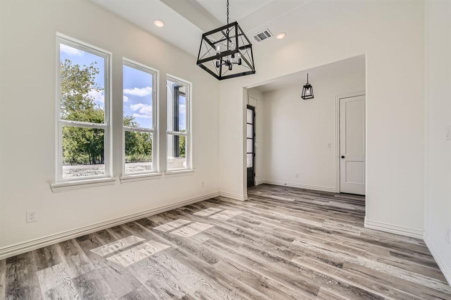 Unfurnished room with a healthy amount of sunlight, light hardwood / wood-style floors, and an inviting chandelier