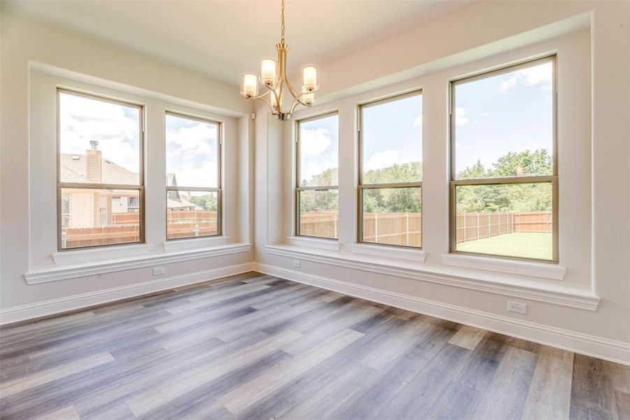 Unfurnished dining area with an inviting chandelier and hardwood / wood-style floors