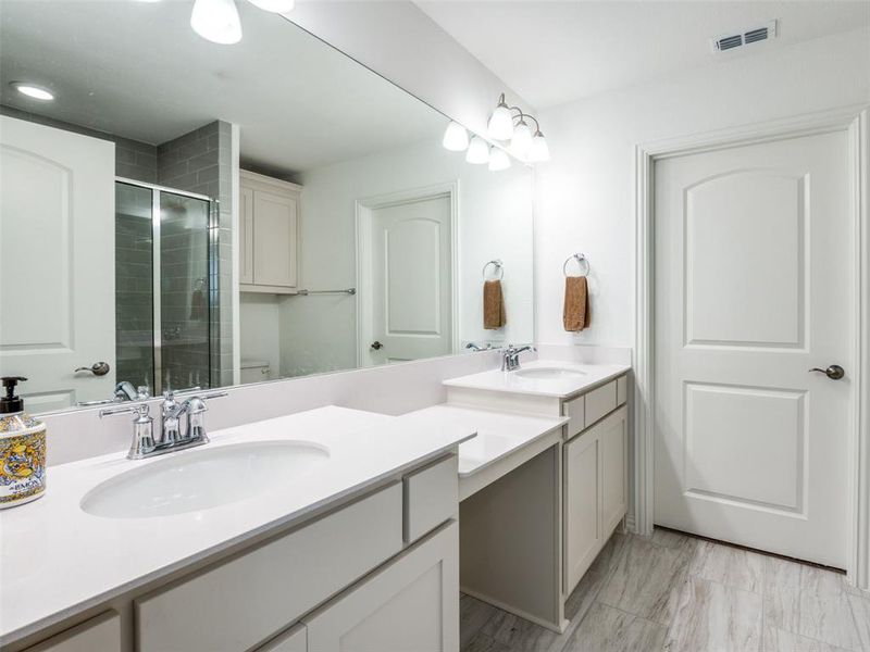 Primary Bathwith dual sinks and tiled shower with bench