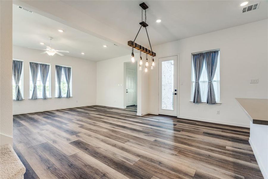 Unfurnished dining area featuring a healthy amount of sunlight, ceiling fan, and dark wood-type flooring