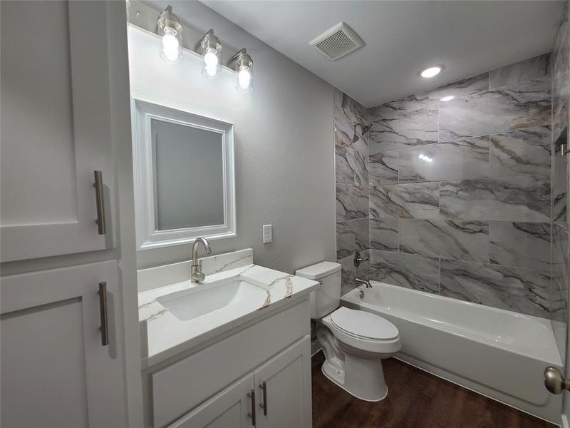 Guest full bathroom featuring tiled shower, vanity, and additional cabinetry for storage