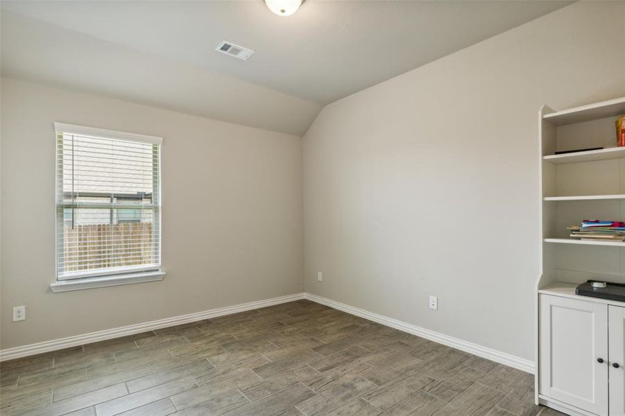 Empty room featuring vaulted ceiling and hardwood / wood-style flooring