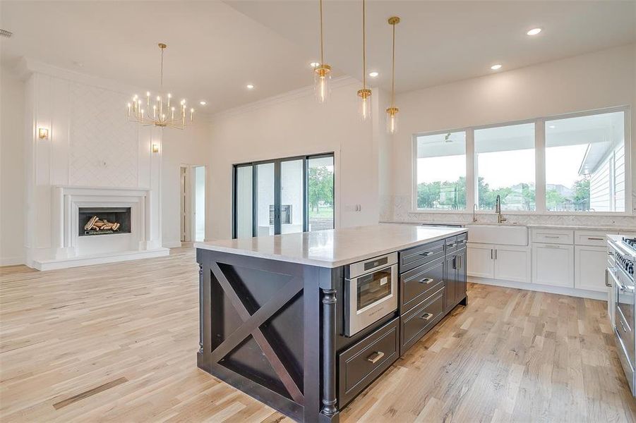 Kitchen with white cabinetry, a center island, hanging light fixtures, and light wood-type flooring