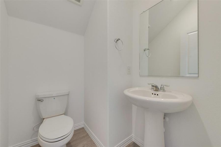 Bathroom with toilet, wood-type flooring, lofted ceiling, and sink