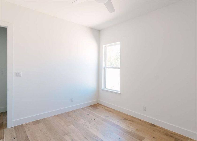 Empty room featuring light wood-type flooring and ceiling fan