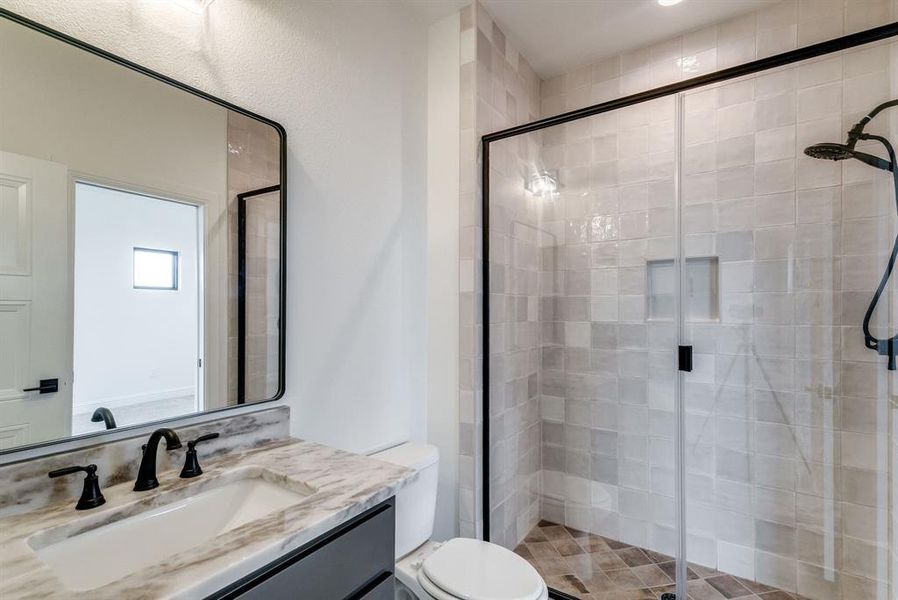 Bathroom with vanity, a shower with shower door, and toilet