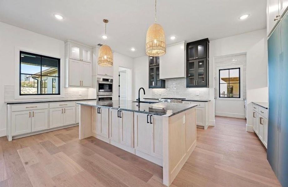 Kitchen with a kitchen island with sink, white cabinetry, light hardwood / wood-style flooring, and sink