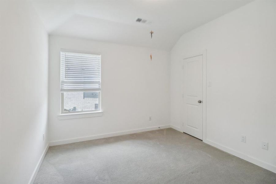 Spare room featuring carpet floors and vaulted ceiling