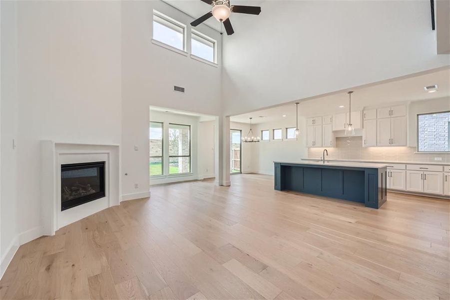 Unfurnished living room featuring a healthy amount of sunlight, light hardwood / wood-style floors, and ceiling fan with notable chandelier