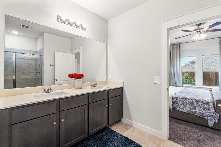 Bathroom featuring vanity, ceiling fan, tile patterned floors, and a shower with door