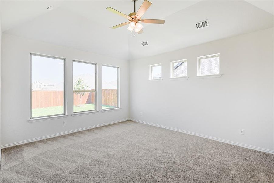 Empty room with vaulted ceiling, ceiling fan, and light colored carpet