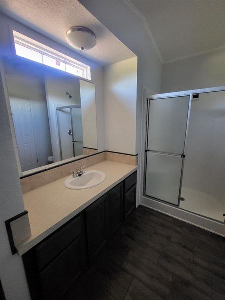 Bathroom featuring a textured ceiling, vanity, an enclosed shower, and wood-type flooring