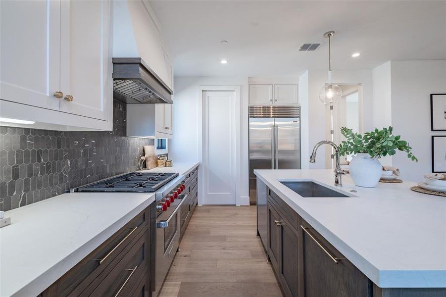 Kitchen featuring quartz countertops, premium range hood, high end appliances, Sub zero fridge, sink, and light wood flooring