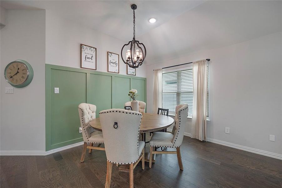 Dining room featuring dark wood-type flooring, lofted ceiling, and a notable chandelier