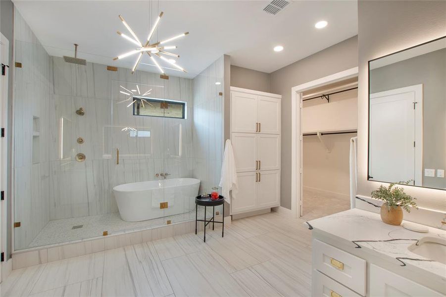 Bathroom with tile floors, walk in shower, an inviting chandelier, and vanity