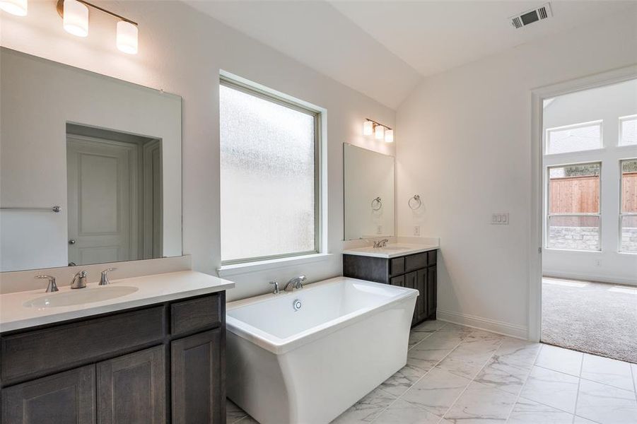 Bathroom featuring a bath to relax in, tile flooring, dual vanity, and lofted ceiling