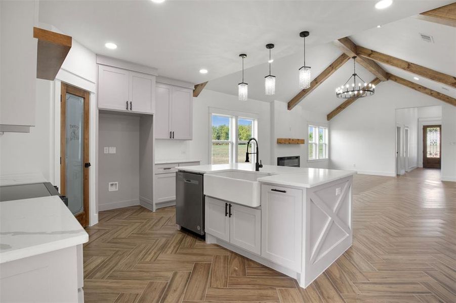 Kitchen featuring lofted ceiling with beams, pendant lighting, white cabinetry, and stainless steel dishwasher