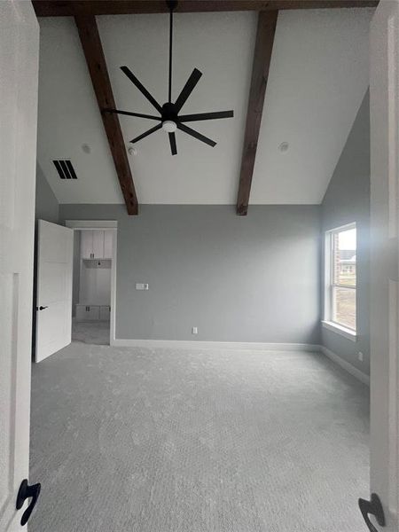 Unfurnished living room featuring beamed ceiling, carpet, high vaulted ceiling, and ceiling fan