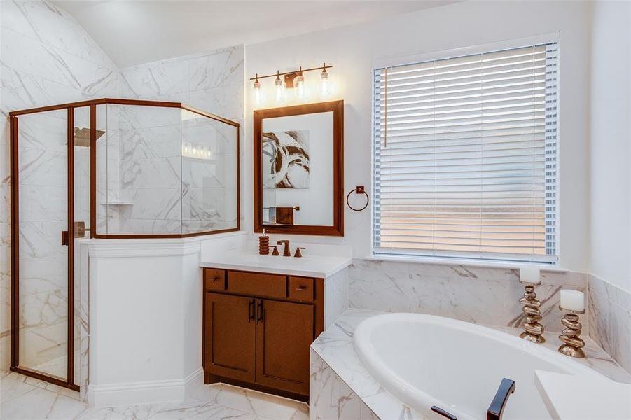 Bathroom with tile floors, a wealth of natural light, separate shower and tub, and vanity with extensive cabinet space