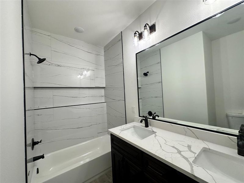 Full bathroom with toilet, tiled shower / bath combo, and vanity