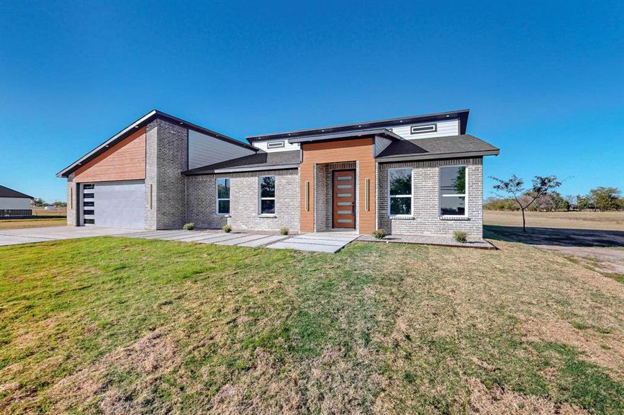 View of front of house featuring a front lawn and a garage