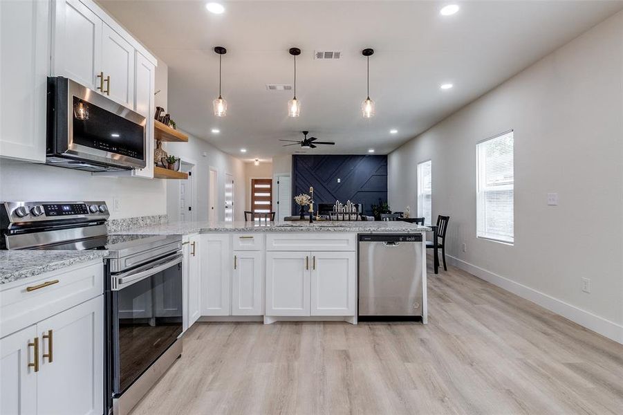 Kitchen featuring light hardwood / wood-style floors, white cabinetry, stainless steel appliances, kitchen peninsula, and ceiling fan