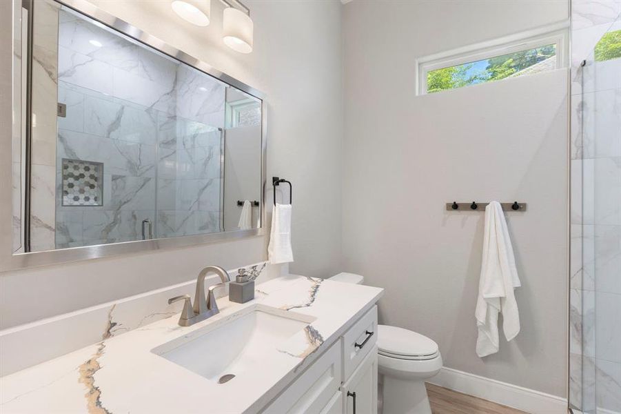 This bathroom is between the two downstairs bedrooms and boasts a large countertop, huge walk-in shower with porcelain tiles, and a linen nook behind the door to place all your towels/bath items.