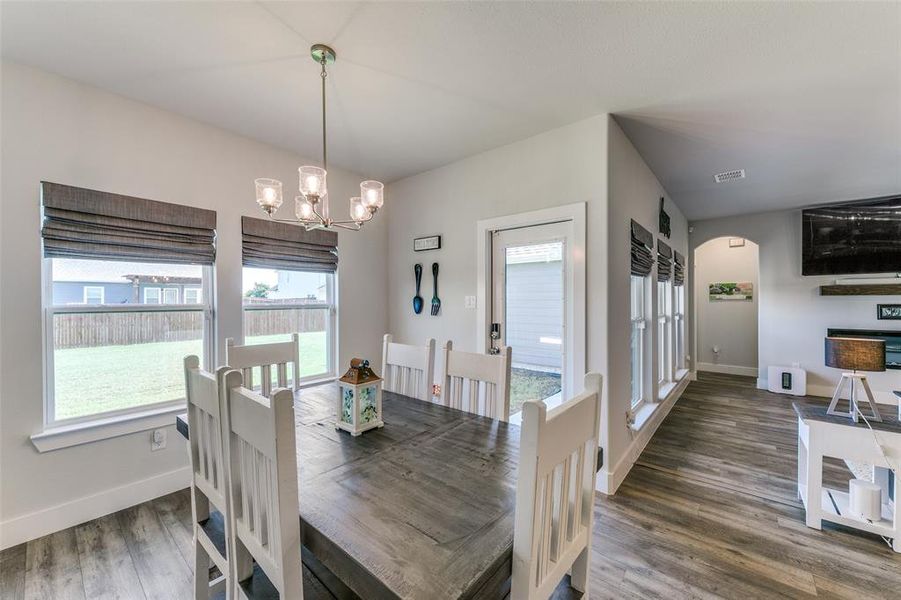 Dining room with an inviting chandelier, dark hardwood / wood-style floors, and a wealth of natural light