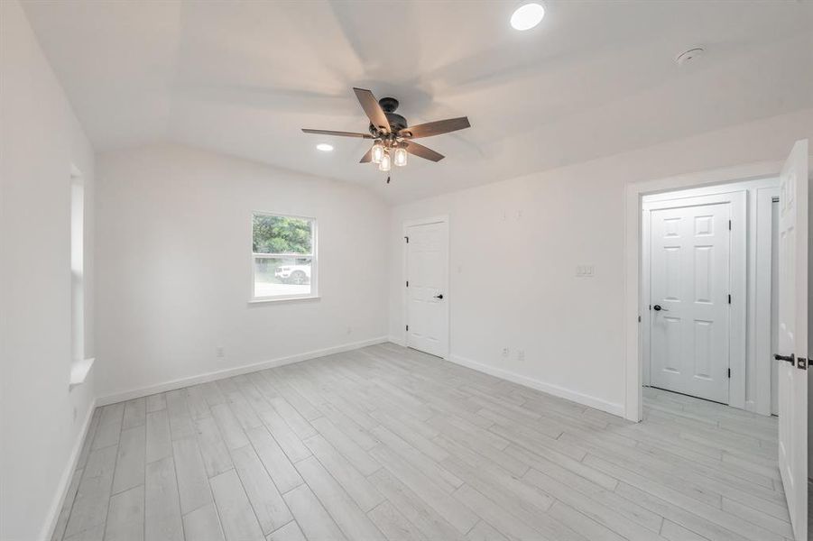 Unfurnished room featuring light hardwood / wood-style flooring, lofted ceiling, and ceiling fan