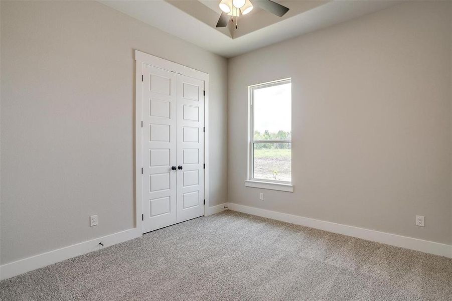 Carpeted spare room featuring ceiling fan