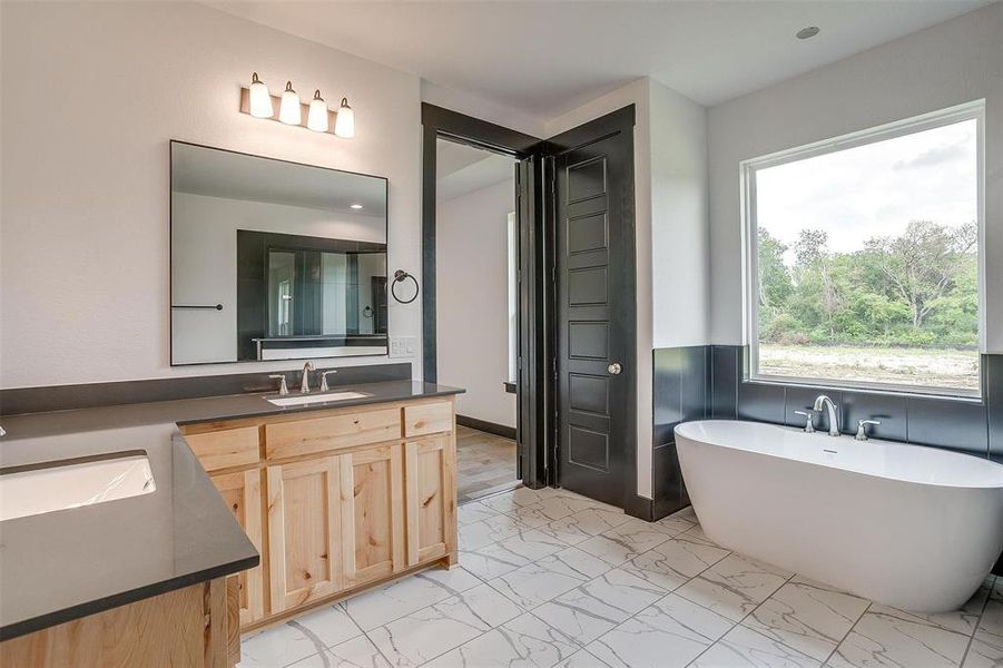 Bathroom with tile flooring, vanity, and a bath