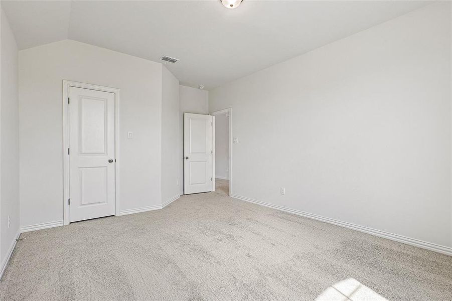 Unfurnished bedroom with light carpet and vaulted ceiling