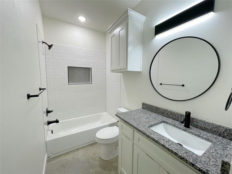 Full bathroom with toilet, tiled shower / bath combo, and vanity