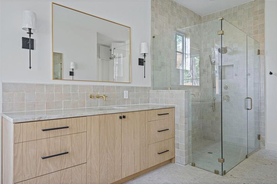 Bathroom featuring a shower with door, vanity, and tasteful backsplash