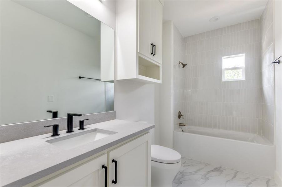 Full bathroom with tiled shower / bath, tile flooring, toilet, and vanity