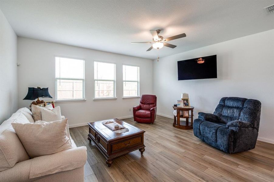 Living room with ceiling fan and light hardwood / wood-style flooring