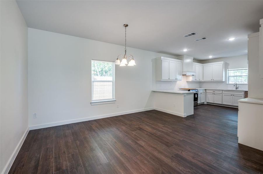 Kitchen featuring dark wood-type flooring, white cabinetry, stainless steel electric stove, and kitchen peninsula