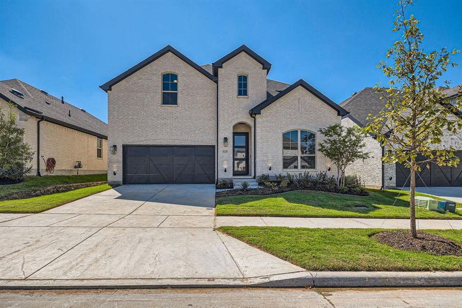 French country inspired facade featuring a front yard and a garage