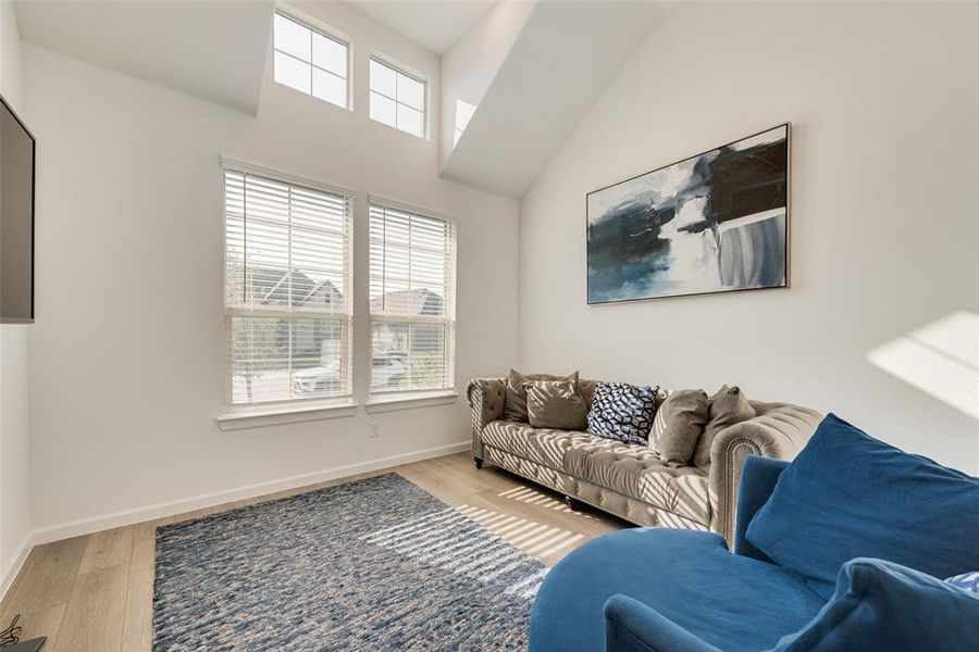 Living room with high vaulted ceiling and light hardwood / wood-style floors