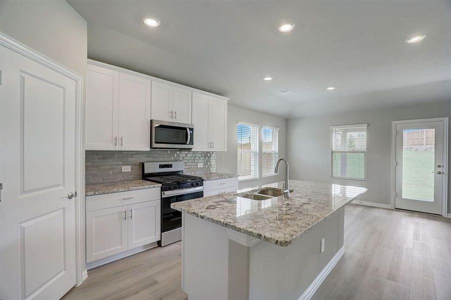 Kitchen featuring appliances with stainless steel finishes, a kitchen island with sink, sink, and white cabinetry