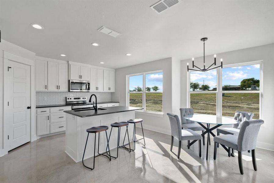 Kitchen featuring white cabinetry, appliances with stainless steel finishes, sink, and hanging light fixtures