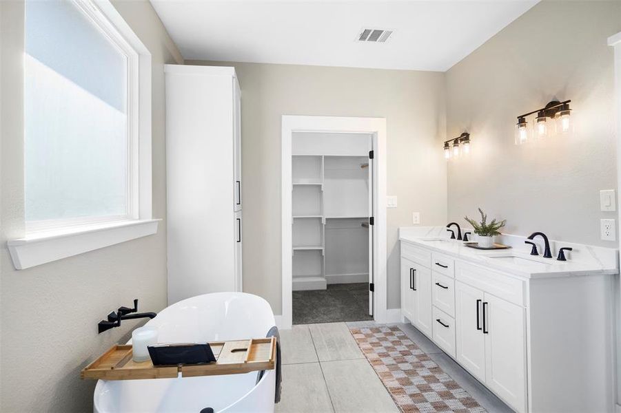 Bathroom featuring a bath, tile patterned floors, and vanity