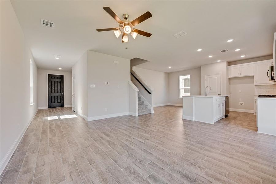 Unfurnished living room featuring ceiling fan, light wood-type flooring, and sink