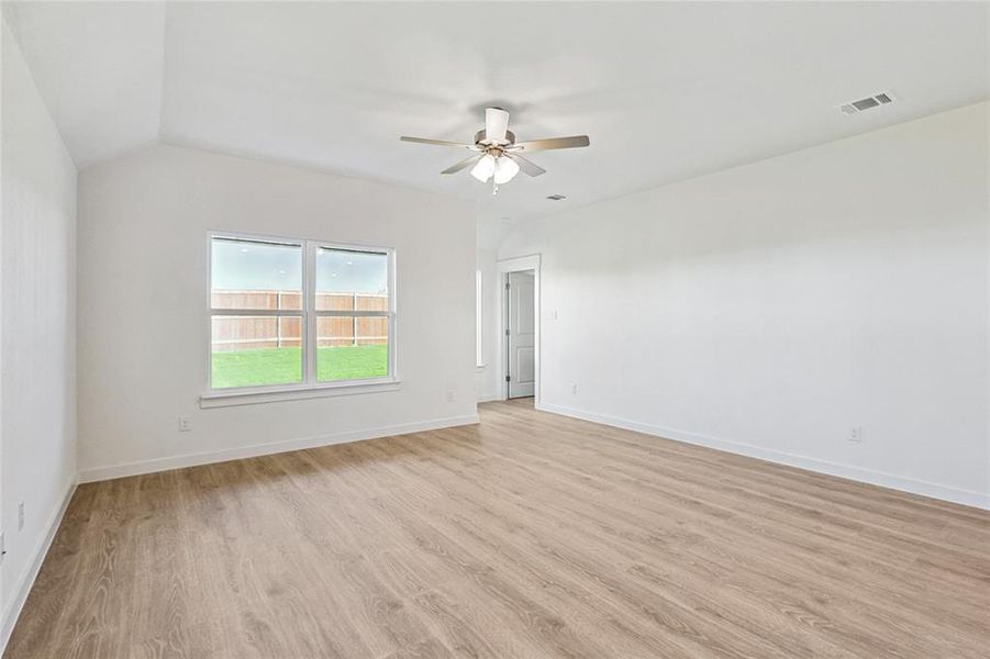 Empty room with light wood-type flooring, ceiling fan, and vaulted ceiling