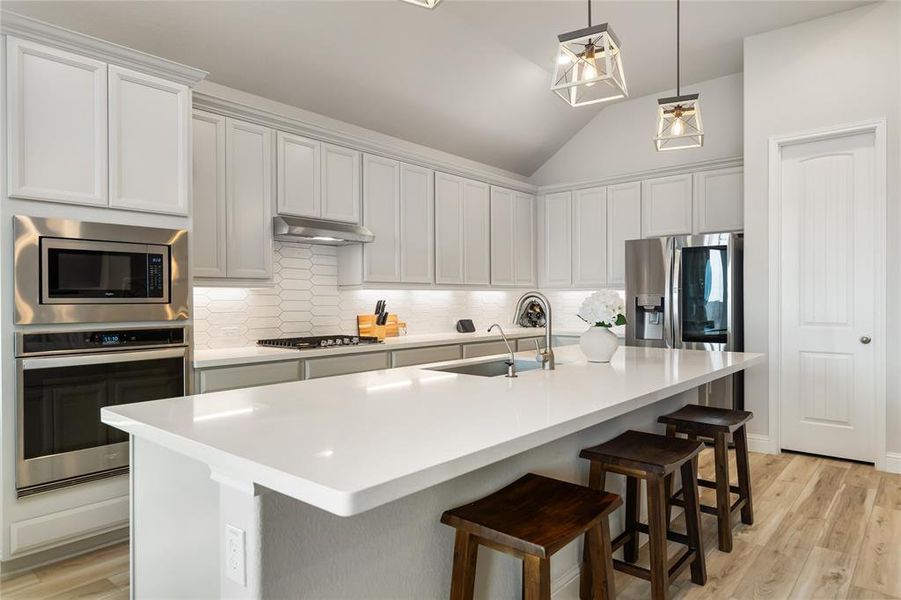White counters, cabinets, and backsplash, plus under-cabinet lighting, keep the kitchen bright and airy
