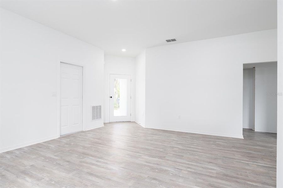 View of great room, garage door to the left and front door view from inside looking out.