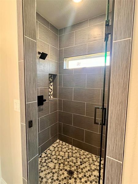 Bathroom with a shower with shower door and a textured ceiling