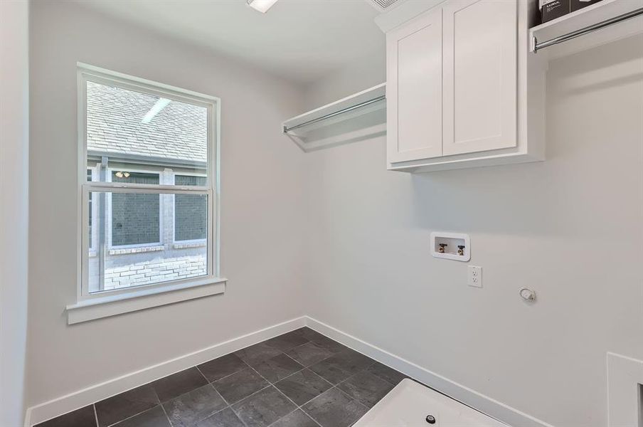 Clothes washing area featuring hookup for a washing machine and cabinets